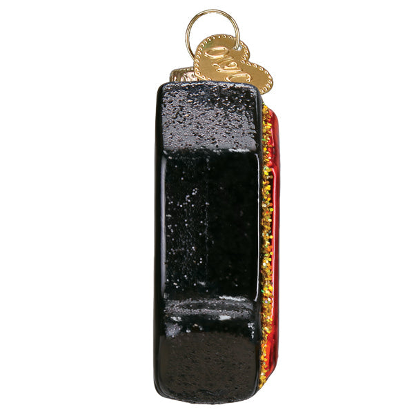 Side view of an AC/DC Old World Christmas Ornament 38074 shaped like a lightning bolt, featuring a black exterior with a glittery red edge and a small gold heart-shaped charm at the top.