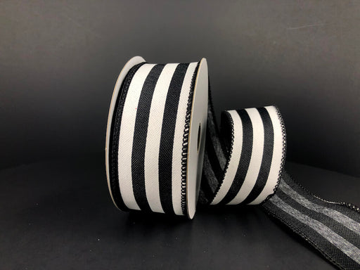 A partially unwound spool of 1.5X10Y Black Linen/White Wide Cabana Stripes Ribbon 41325-09-21 rests on a dark surface, its thick linen boasting bold, evenly spaced stripes against a shadowy backdrop.
