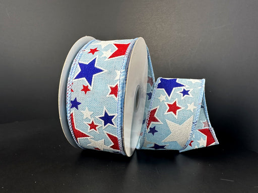 The 1.5X10Y Lt Blue Navy Red White Linen Glitter Stars Ribbon features red, white, and blue stars on a light blue background, elegantly coiled and perfect for adding sparkle and charm to any decor with its wired star pattern against a dark surface.