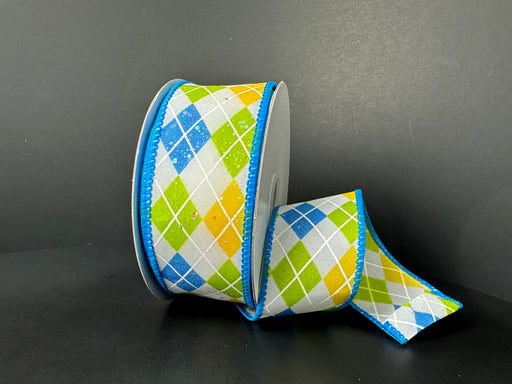 A partially unrolled spool of 1.5X10Y White Iridescent Turquoise Yellow Glitter Satin Argyle Diamonds Ribbon 41530-09-39 is set against a dark backdrop, featuring a vibrant pattern in green, blue, yellow, and white with blue edges, giving it a cheerful appearance.
