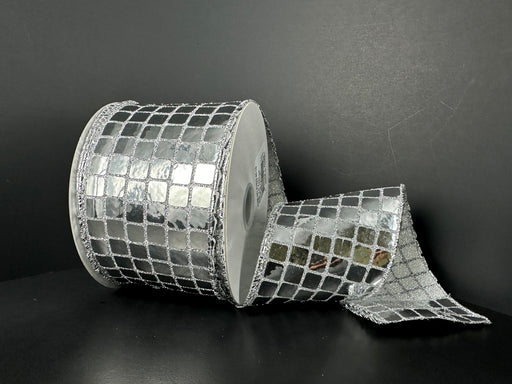 A roll of 2.5X10Y Silver Discoball Sequins Ribbon (41533-40-16) sits against a dark background, partially unrolled to reveal its shiny, mirror-like surface with a grid of silver squares, reminiscent of a disco ball.