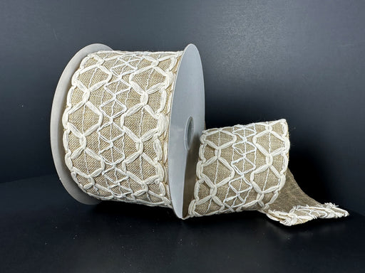 A spool of 2.5x10Y Ivory Burlap Natural Scallop Linen Ribbon (41538-40-15) features a geometric scallop pattern in white thread on black. Wired and decorative, the ribbon is partially unfurled to beautifully display its intricate design.