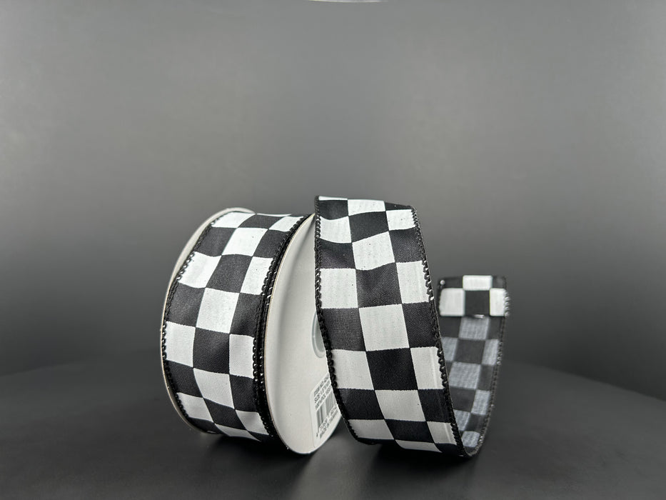 Two rolls of 1.5X10Y Black Satin/White Race Checks Ribbon (42437-09-21) are against a gray background: one upright, the other partially unrolled to display its black and white checkered pattern.