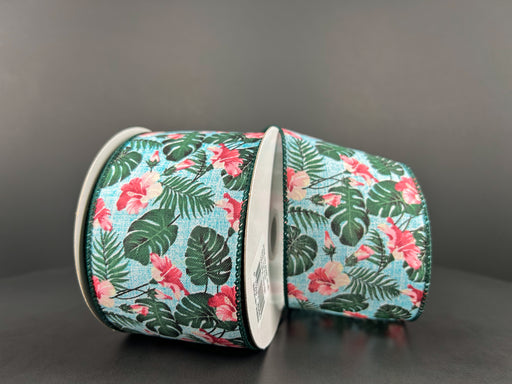 Two spools of aqua linen ribbon, 2.5X10Y in size, feature a tropical hibiscus and monstera leaf pattern on a light blue background against a dark backdrop (Product: 42447-40-45).