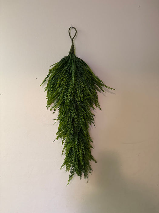The Green Plastic Beed Grass Swag 28 Inches (PG552550-063) hangs upside down from a loop against a plain off-white wall.