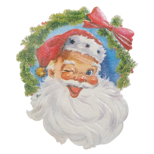 Illustration of Santa Claus winking and smiling, framed by a green wreath with a red bow. The 18" Santa Head Cut Out Wall Art 4525979 from the Treasured Moments Collection is perfect festive metal wall decor.
