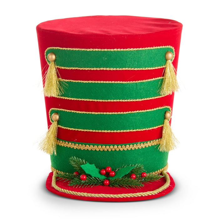 The 10.75″ Ringmaster Hat Christmas Tree Topper (RAZ 4616097) features a tall design in red and green felt, adorned with gold trim, gold tassels, and festive holly accents with red berries, evoking the look of a classic toy soldier or ringmaster’s hat—perfect as a charming tree topper or holiday decor accent.
