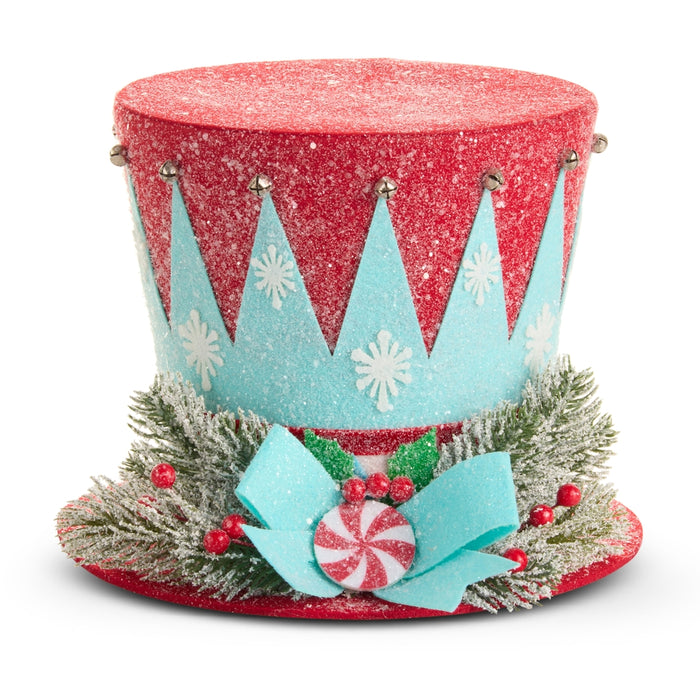 Add some details from the product data and refocus the sentence as follows: The 10″ Merry Peppermint Top Hat Christmas Decoration (RAZ 4616121) features a festive red and blue design adorned with white snowflakes, frosted greenery, red berries, a blue ribbon, and a peppermint candy ornament. Dusted with glitter for extra holiday cheer, this charming piece is perfect as wreath décor or as a delightful Christmas tree topper.