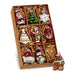 A 2″ box of nine glass Christmas icon ornaments (RAZ 4619184), featuring festive designs like Santa, a tree, a snowflake, and a gingerbread man, beautifully arranged on brown shredded paper.
