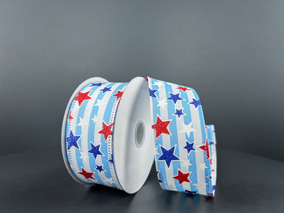 Two spools of 1.5X10Y White Linen-Lt Blue Stripe/Red White and Blue Glitter Stars Ribbon stand upright on an elegant dark gray surface.