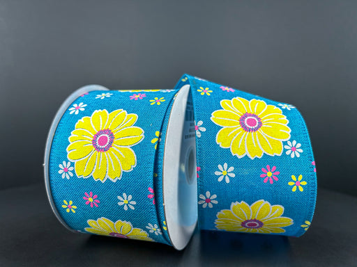 Against a dark background, two spools of the 2.5"X10Y Turquoise Linen/Giant Daisies Ribbon 46412-40-39 display their blue shades and vibrant yellow daisies prominently surrounded by smaller white and pink flowers.