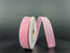 The 7/8X10Y Lt Pink Candy Glittered Satin Ribbon 46420-05-03 spool stands upright against a dark background, with the partially unwound ribbon revealing its sparkly texture.