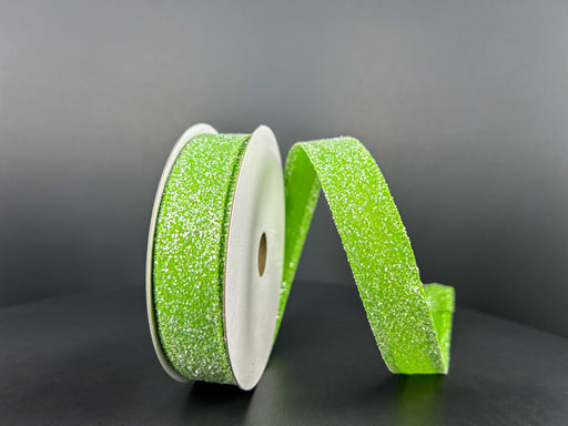 Two spools of 7/8X10Y Lime Candy Glittered Satin Ribbon 46420-05-09, one upright and one lying on a dark gray background. The sparkly ribbon with glittery texture and satin finish is partially unrolled, forming a gentle wave.