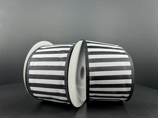 Two spools of 2.5X10Y Black Satin-White Stripes/Black Edge Ribbon 46425-40-21 stand upright against a dark background, leaning against each other and showcasing the bold horizontal stripe pattern beautifully.