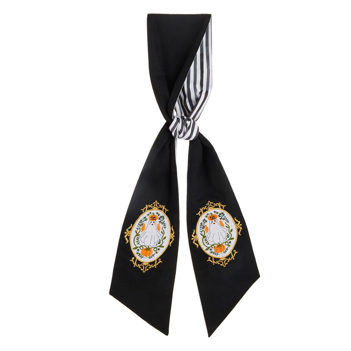The 60″ A Sweet Haunting Halloween Reversible Wreath Sash (RAZ 4656345) features a black fabric adorned with white and gold embroidered cat designs, elegantly framed by ornate gold ovals, while the reverse side reveals a striking black-and-white stripe pattern at the knot. This RAZ Exclusive accessory is perfect for adding stylish flair to your Halloween wreath and can also be worn as a chic scarf.