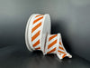 Two white circular boxes are decorated with 1.5x10Y orange flat all glitter/white diagonal stripe/white fuzz stripe ribbon (51503-09-01). One box is upright; the other lies on its side with ribbon cascading onto the surface.