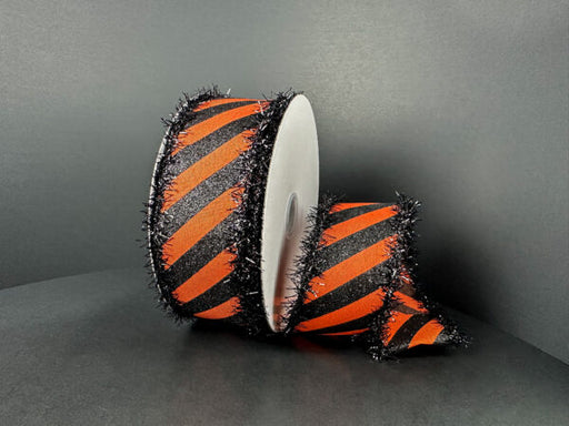 Two rolls of 1.5x10Y OrangeSatin/Black Glitter Diagonal Stripe ribbon with black tinsel edges (51504-09-20) are displayed against a dark background: one upright, the other partially unspooled.