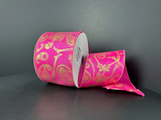 A partially unrolled 2.5x10y fuchsia satin ribbon with a black skull paisley pattern (51513-40-28) is displayed against a plain dark background.
