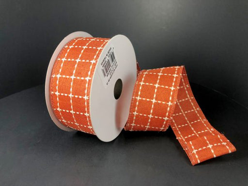 A partially unrolled spool of 1.5X10Y Dark Orange CreamStark Plaid Ribbon (61025-09-19) with a white checkered pattern is displayed against a plain black background.