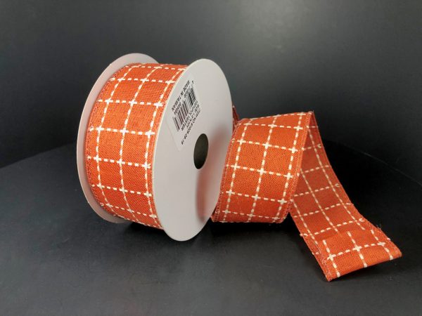 A partially unrolled spool of 1.5X10Y Dark Orange CreamStark Plaid Ribbon (61025-09-19) with a white checkered pattern is displayed against a plain black background.
