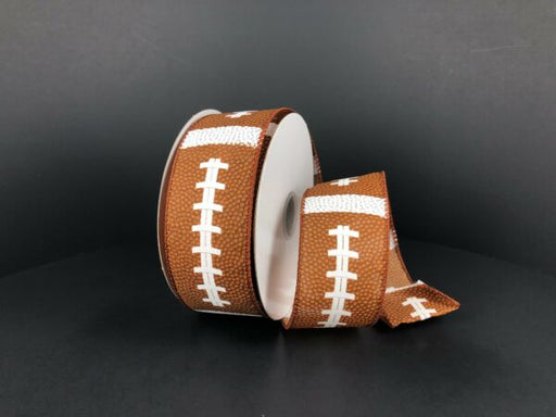 A partially unrolled 1.5X10Y Brown and White Football Thick Satin Ribbon (61228-09-38) with a white stitching pattern, displayed against a plain black background.