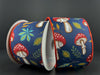 Two spools of 2.5X10Y Navy Satin/Earthy Fall Mushrooms Ribbon 61411-40-38 rest on a dark surface, displaying vibrant designs with red and white mushrooms, green and yellow leaves, and blue accents on a navy background. The navy wired ribbon is trimmed elegantly in red.