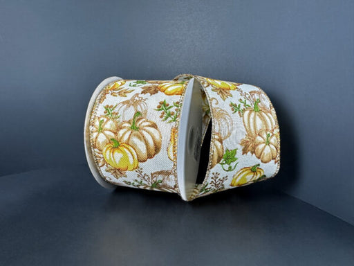 Two rolls of 2.5 x 10Y Cream Linen Ribbon (61512-40-35) featuring yellow and bronze gold pumpkins, green leaves, and brown acorns on a white background, displayed on a dark gray surface.