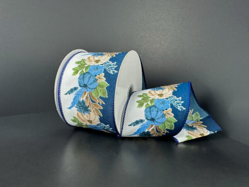 A roll of 2.5X10Y Ivory Satin/Blue Fall Pampas Ribbon (61522-40-27) sits on a dark gray surface, set against a plain gray background.