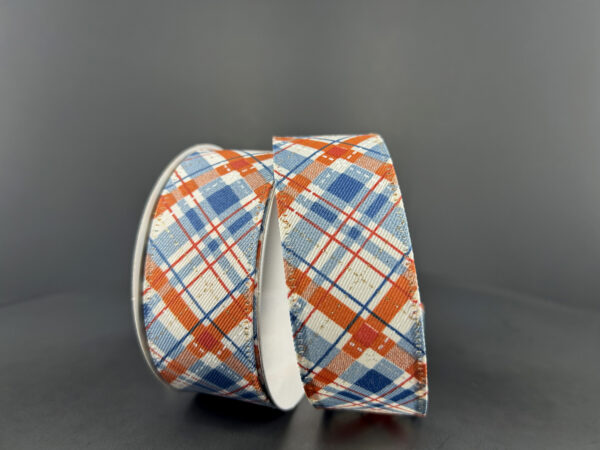Two rolls of 1.5X10Y Cream Rust Blue Gold Argyle Ribbon (65432-09-05) featuring a cream diagonal linen pattern with rust, blue, and gold accents are displayed upright and leaning together against a plain dark background.