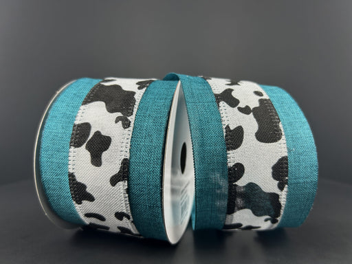 Two spools of 2.5X10Y Bw Cow Print Linen/Teal Edge Ribbon are side by side against a dark gray background. These wired ribbons add a whimsical touch to any project.