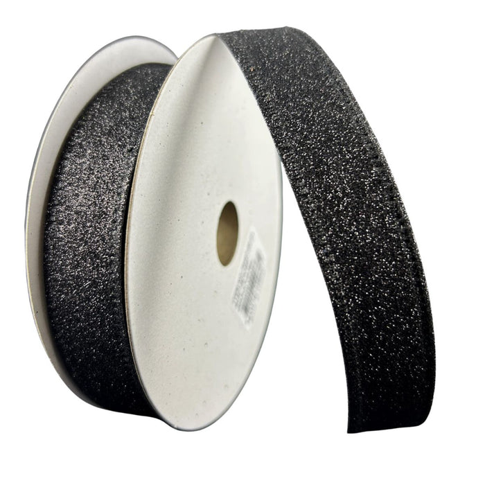A roll of 7/8" black ribbon with flat glitter and wired edges, partially unrolled to display its sparkly surface.