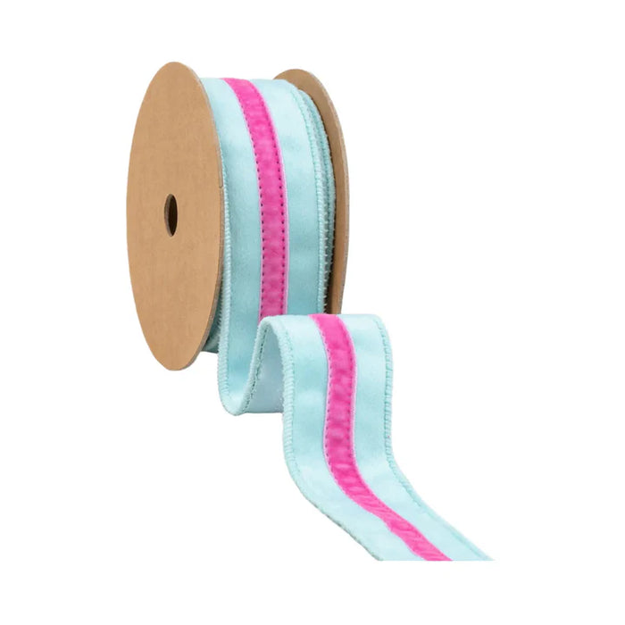 The 1.5 Inch Blue Velvet Ribbon with Pink Center Stripe (7020W-305-38E) features light blue edges and a bright pink center, partially unrolled on a reel—perfect for wreaths, displayed against a white background.
