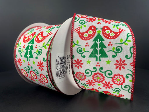 A spool of the 2.5"X10Y White Satin/Red-Green Christmas Tree-Red Demask 71388-40-01 wired ribbon showcases a festive design with red and green birds, trees, and floral patterns. The white satin backdrop highlights the Christmas tree motifs as it sits partially unrolled against a dark background.