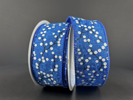 A spool of 1.5X10Y Royal Blue Linen/White Glitter Berries ribbon sits against a dark background, partially unwound to reveal its elegant berry and branch design, adding a touch of sophistication.
