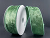 The 1.5X10Y Sage Lush Velvet Ribbon (72430-09-06) is shown with its white core against a dark gray backdrop, its shiny, textured sage material unspooled and elegantly curved to the side.