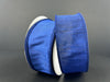 Two rolls of 1.5X10Y Navy Faux Dupioni Ribbon 72434-09-27 stand against a dark background, with one textured spool partially unrolled and draped over the other, both positioned upright to add dimension to the scene.