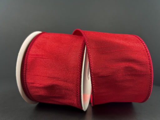 Two rolls of 2.5X10Y Red Faux Dupioni Ribbon (Product ID: 72434-40-12) are neatly wound and resting against each other on a plain dark background.