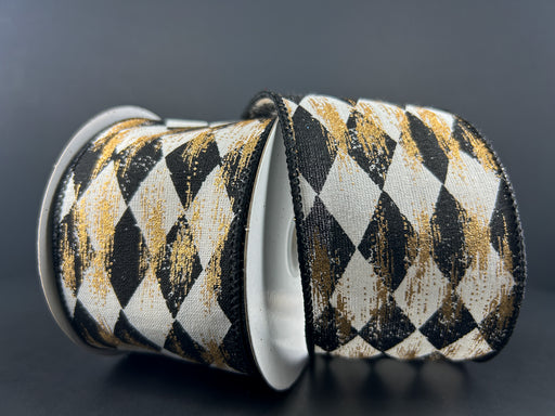 Two spools of 2.5″ x 10 yard cream canvas ribbon, featuring a black faded harlequin pattern with gold metallic accents (72437-40-20), are displayed against a dark background. The refined design of this ribbon brings an elegant touch of sophistication to any project.