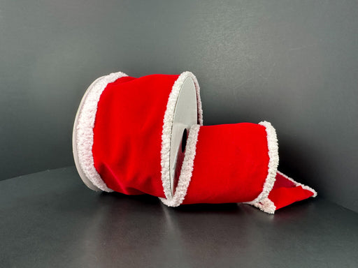 A 2.5 x 10 yd Red Velvet White Super Fuzz Edge Ribbon (72522-40-13), with fluffy trim reminiscent of Santa’s suit, lies on its side against a dark gray background.