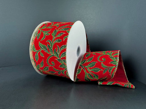 A partially unrolled 2.5X10Y Red Velvet/Lime-Hunter-Gold Vine Swirls Ribbon (72555-40-12) with a red background and glittery green and gold leaf patterns is shown against a dark, plain surface.