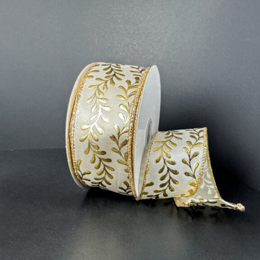 A spool of 1.5X10Y Ivory Satin/Gold Embossed Vines Ribbon (73528-09-41) with a gold leaf pattern and gold edges rests against a dark background, partially unrolled and elegantly draping to the side.