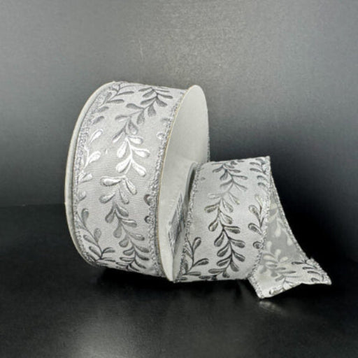 A roll of 1.5X10Y White Satin/Silver Embossed Vines Ribbon (73528-09-42) is shown against a dark background, with a portion unrolled and gracefully draped to highlight its elegant silver vine pattern.