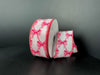 A spool of 1.5X10Y White Ponche Satin/Pink Bows Ribbon 73543-09-03 features pink bows on white satin, with one end unrolled and curved beside the spool, set against a plain dark background.