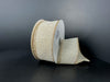A partially unrolled spool of 1.5X10Y Ribbed Ivory-Gold Metallic Linen Ribbon (73544-09-14) with gold edges rests on a dark surface against a plain, dark background.