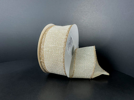 A partially unrolled spool of 1.5X10Y Ribbed Ivory-Gold Metallic Linen Ribbon (73544-09-14) with gold edges rests on a dark surface against a plain, dark background.