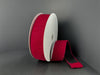 A spool of 1.5x10y Dk Red Ribbed Velvet Ribbon (73561-09-10) stands upright against a dark background, with a length of its deep red ribbon unrolled and lying flat beside it.