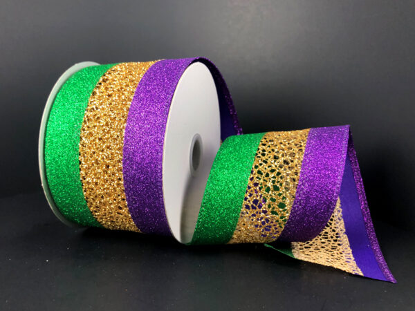 A 2.5x10Y Gold Purple Green Glitter Net Ribbon (75245-40-01) with gold and purple-green glitter edges is partially unrolled, showcasing its shiny, textured surface against a dark background.