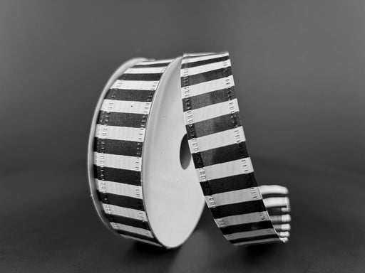A spool of 7/8" Black & White Striped Satin Ribbon (76466-05-21) is partially unwound and stands upright on a dark surface against a plain, dark background.
