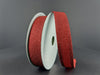 The 7/8"X10Y Red All Flat Glitter Wired Ribbon (76467-05-12) stands upright against a gray background, with some of the red glitter ribbon unrolled and curving gracefully toward the front.