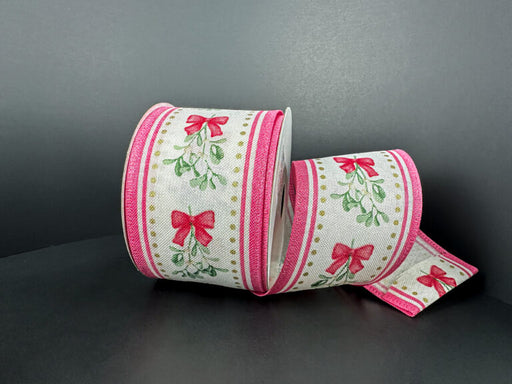 A spool of 2.5X10Y Ivory Linen/Mistletoe Bow/Pink Edge Ribbon 76502-40-44, with red bows and green leaves on white and pink edges, is displayed on a dark surface—perfect for adding festive charm to your decor.